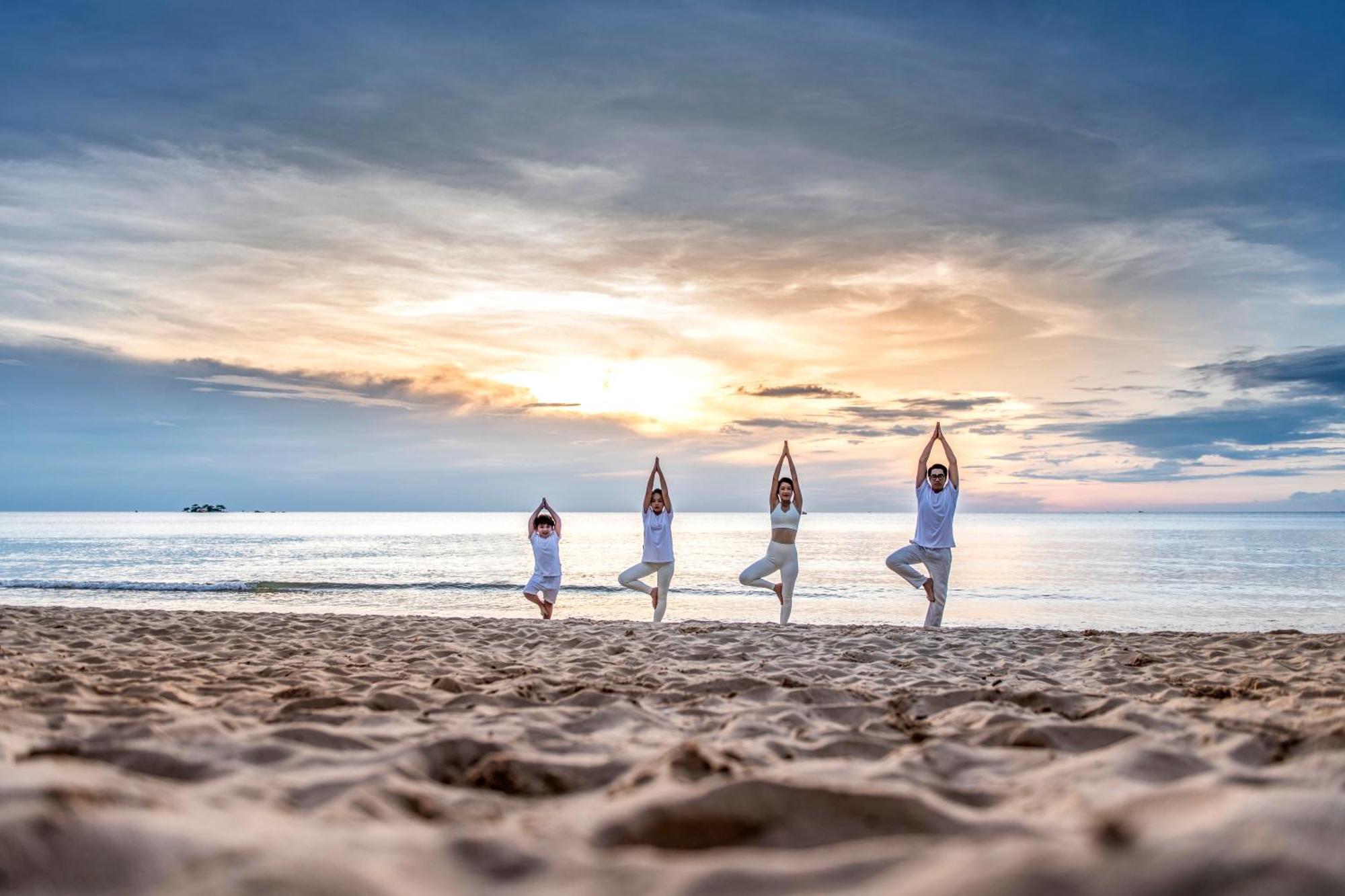 Vinpearl Resort & Spa Phu Quoc Exterior photo Family practicing yoga on the beach